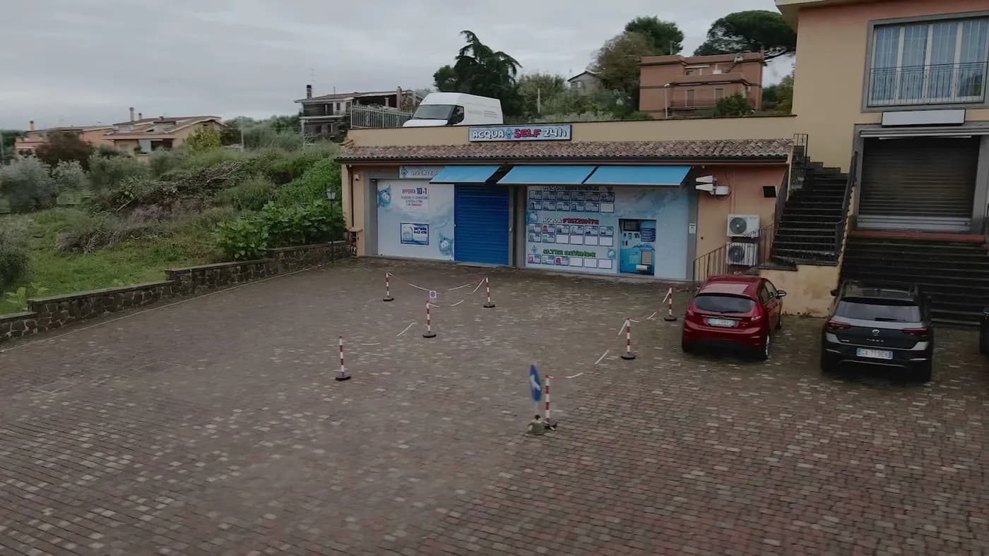Vista esterna del chiosco AcquaSelf24 H24 a Pavona con area di manovra per le auto